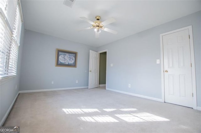 interior space featuring baseboards, a ceiling fan, and light colored carpet