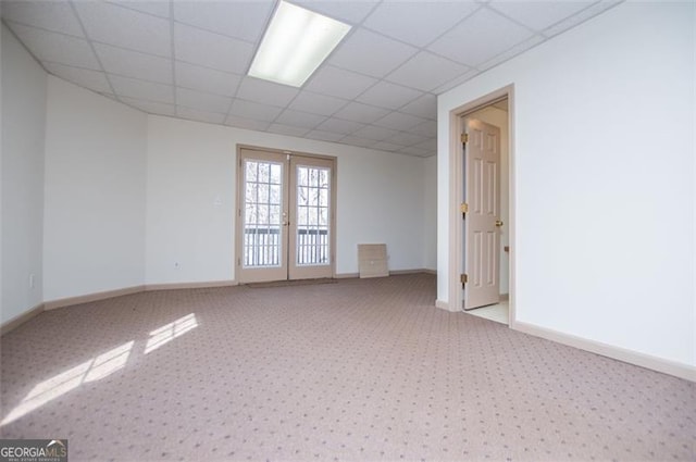 unfurnished room with french doors, a drop ceiling, light carpet, and baseboards