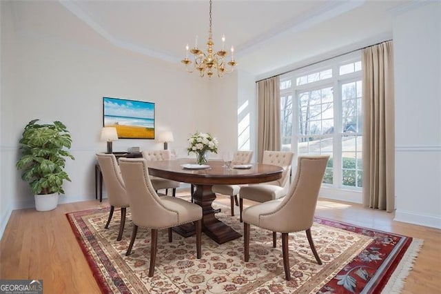 dining space with a chandelier, light wood-style floors, baseboards, and crown molding