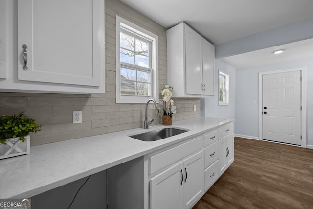 kitchen featuring a sink, backsplash, dark wood-type flooring, and white cabinetry