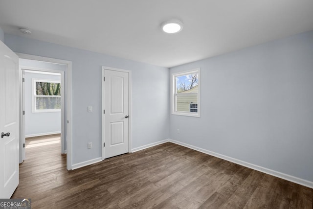 unfurnished bedroom with baseboards and dark wood-style floors