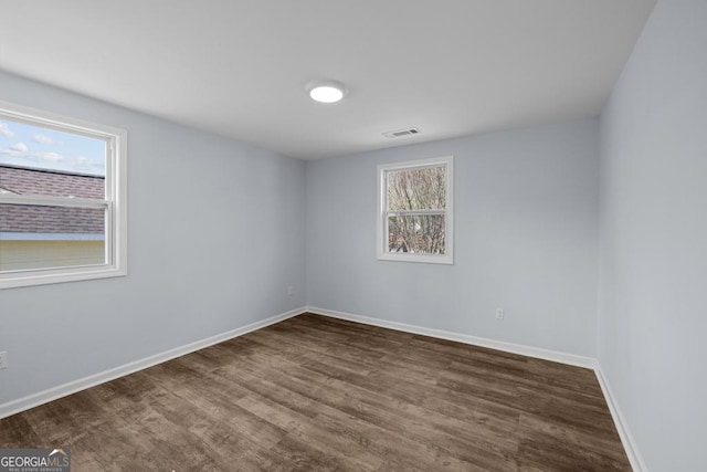 spare room with visible vents, baseboards, and dark wood-style flooring