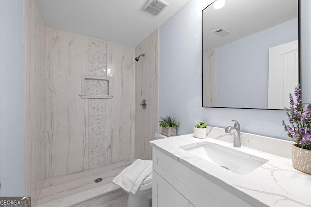 bathroom with vanity, toilet, visible vents, and a marble finish shower