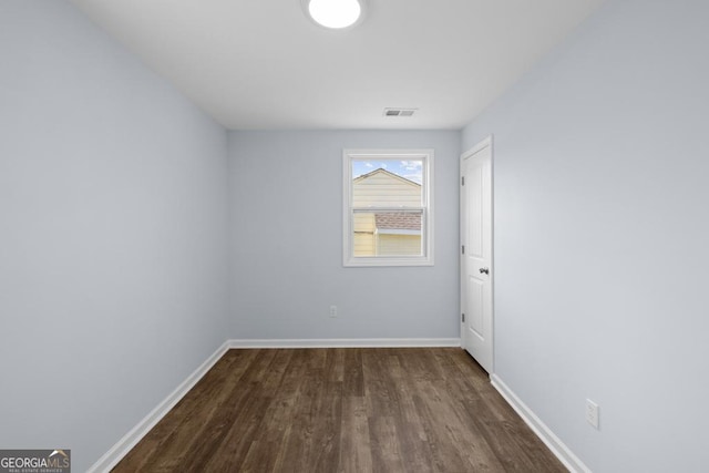 spare room featuring dark wood-style floors, visible vents, and baseboards