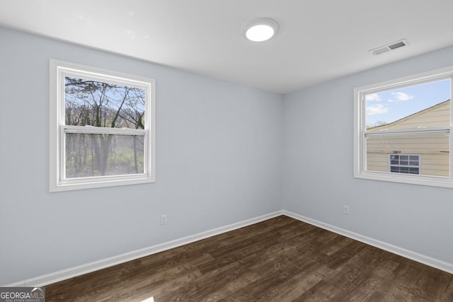 unfurnished room with dark wood-type flooring, baseboards, and visible vents