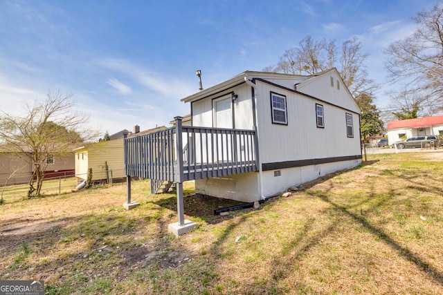 view of home's exterior with crawl space, a lawn, a deck, and fence