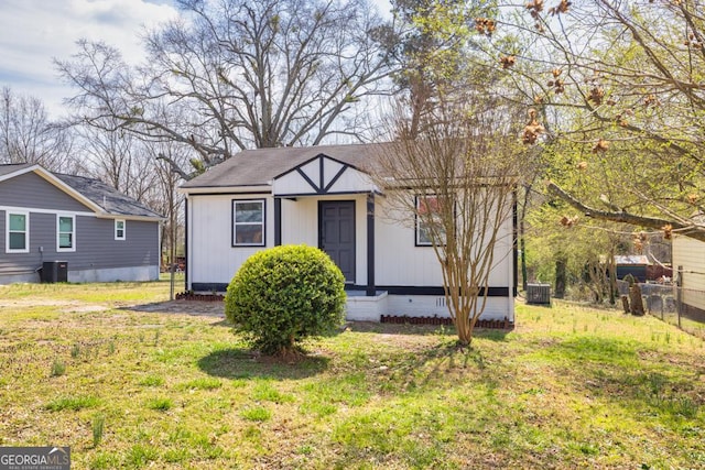 bungalow-style house with a front yard, central AC unit, fence, and crawl space