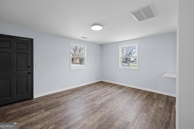 unfurnished room with visible vents, baseboards, and dark wood-style flooring