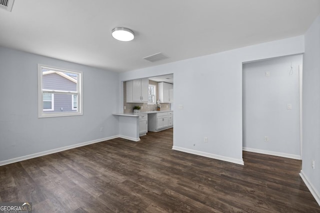 unfurnished living room featuring visible vents, baseboards, and dark wood-style flooring