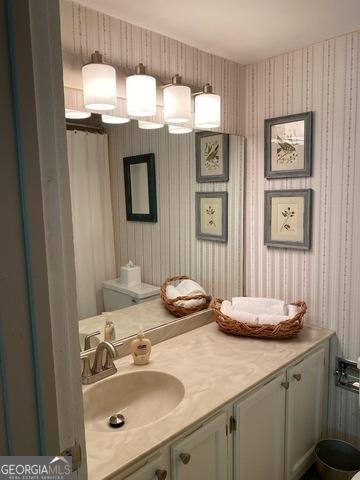 full bath with toilet, vanity, and wallpapered walls