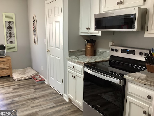 kitchen featuring light wood-style floors, white cabinetry, stainless steel appliances, and light stone counters