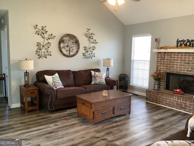 living area featuring vaulted ceiling, dark wood-type flooring, a brick fireplace, and baseboards