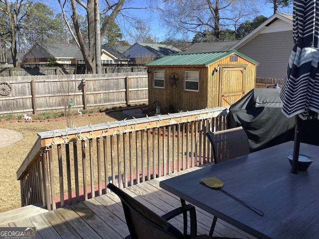 wooden deck with a storage shed, fence, and an outbuilding