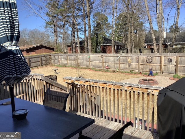 wooden deck with an outdoor fire pit, a patio, area for grilling, a fenced backyard, and outdoor dining space