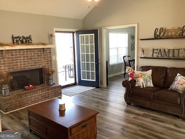 living room with vaulted ceiling, dark wood-type flooring, a brick fireplace, and baseboards