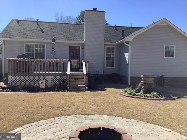 rear view of property featuring a shingled roof, a fire pit, a patio, a chimney, and a wooden deck