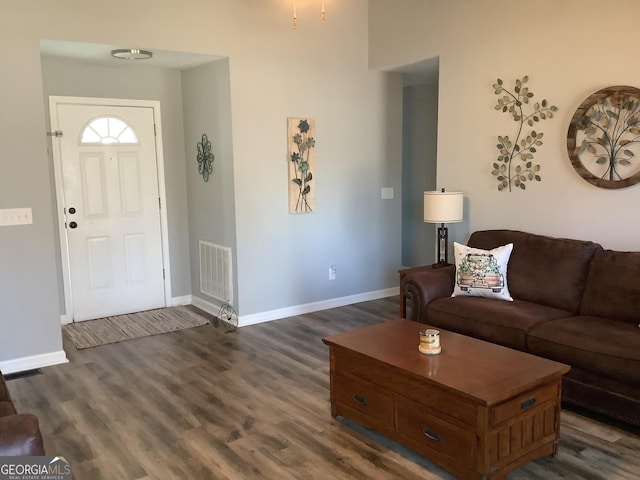 living room with dark wood-style flooring, visible vents, and baseboards