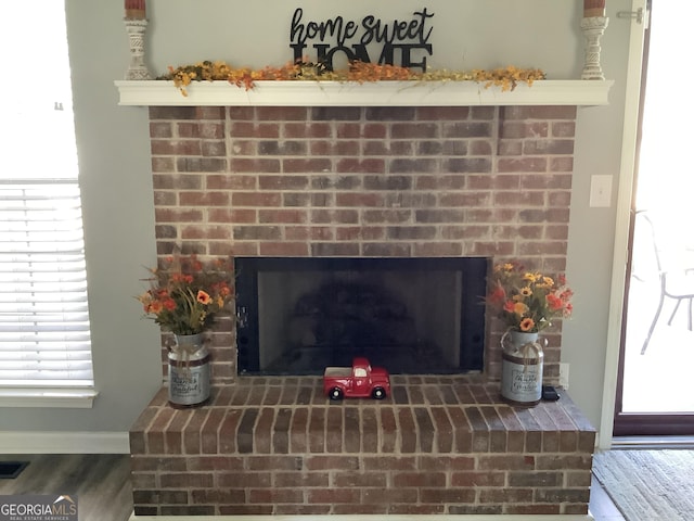 interior details featuring a brick fireplace, wood finished floors, and baseboards