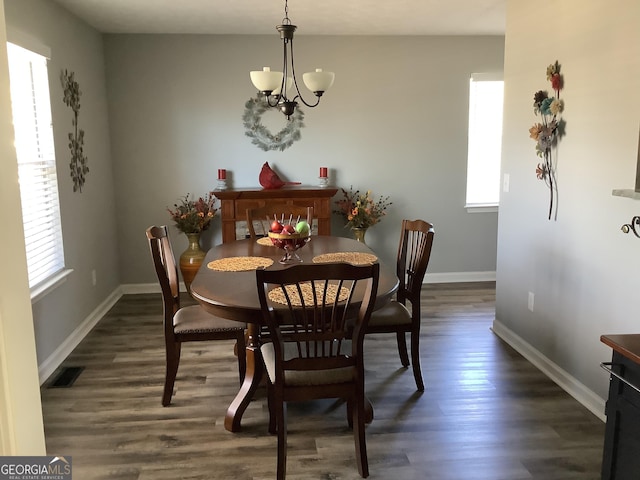 dining room featuring a chandelier, dark wood-type flooring, visible vents, and baseboards