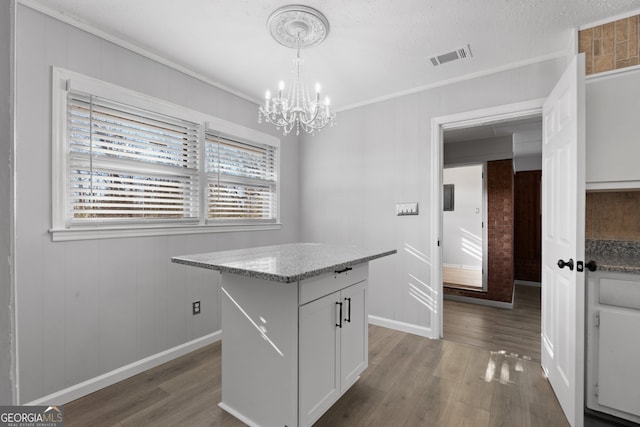 kitchen featuring light stone counters, a center island, pendant lighting, dark wood-type flooring, and white cabinetry