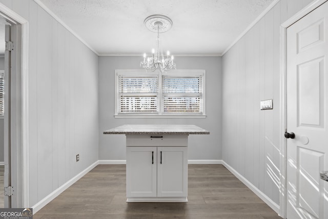 unfurnished dining area with ornamental molding, baseboards, dark wood-style floors, and an inviting chandelier