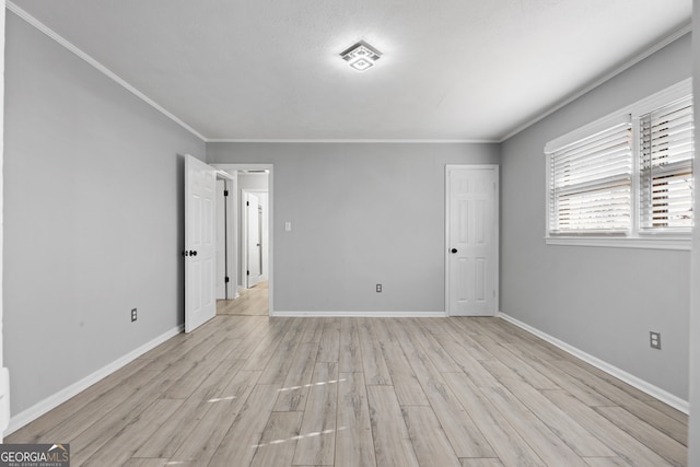 spare room featuring baseboards, light wood-type flooring, visible vents, and crown molding