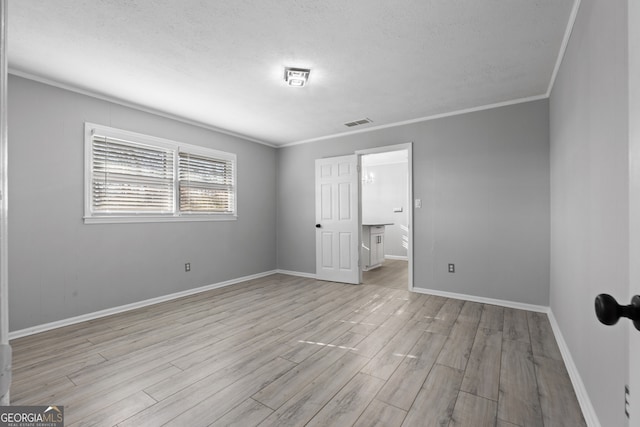 unfurnished bedroom with crown molding, visible vents, light wood-style flooring, a textured ceiling, and baseboards