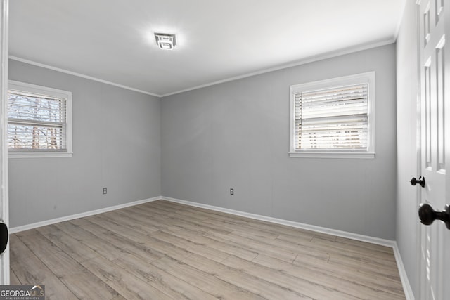 spare room with light wood-type flooring, baseboards, and crown molding