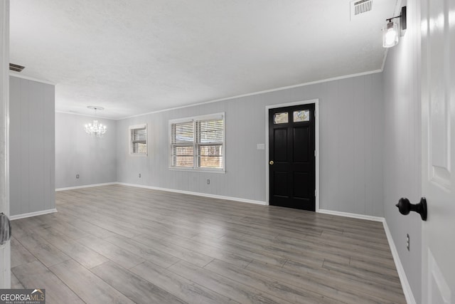 foyer featuring an inviting chandelier, visible vents, and wood finished floors