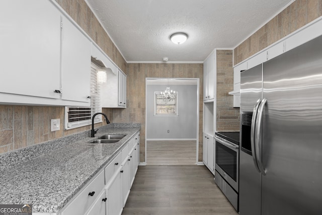 kitchen with appliances with stainless steel finishes, a sink, light stone countertops, and white cabinets