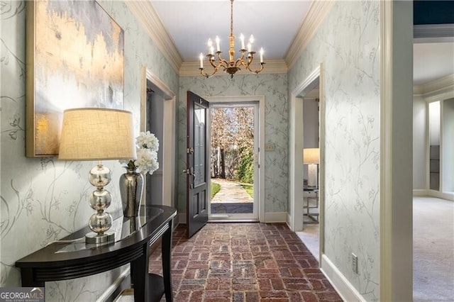 foyer with wallpapered walls, baseboards, ornamental molding, brick floor, and a notable chandelier