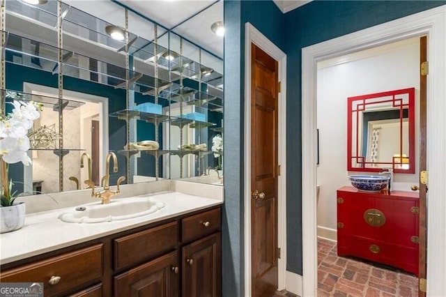 bathroom featuring brick floor, baseboards, and vanity