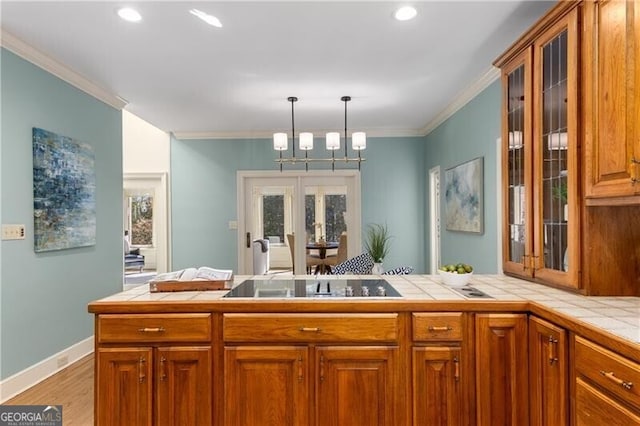 kitchen with tile counters, ornamental molding, and black electric cooktop