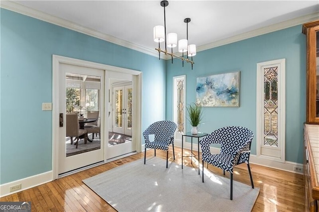 sitting room with french doors, a notable chandelier, ornamental molding, baseboards, and hardwood / wood-style flooring