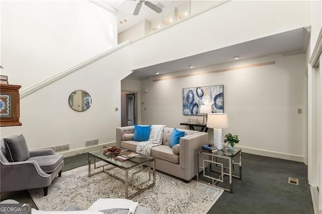 living area with a towering ceiling, baseboards, visible vents, and a ceiling fan