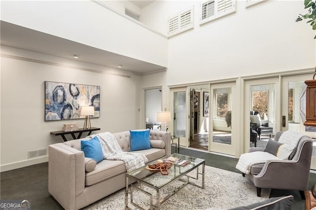 living area featuring baseboards, visible vents, and a high ceiling