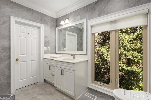 bathroom featuring visible vents, a soaking tub, ornamental molding, vanity, and tile walls