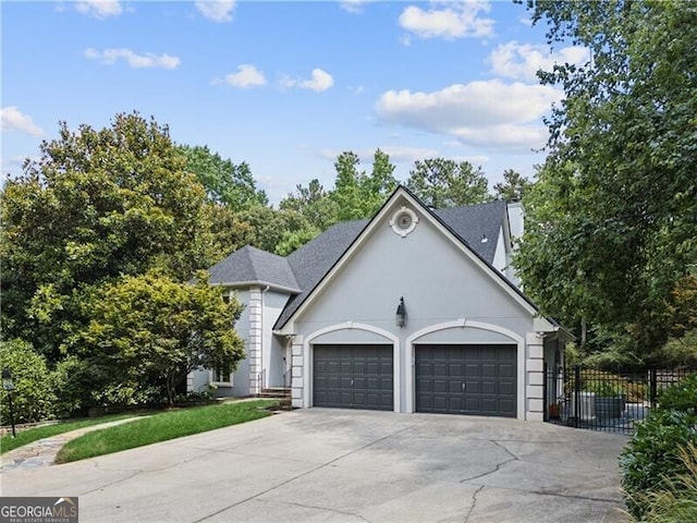 view of front of property with a garage, concrete driveway, fence, and stucco siding