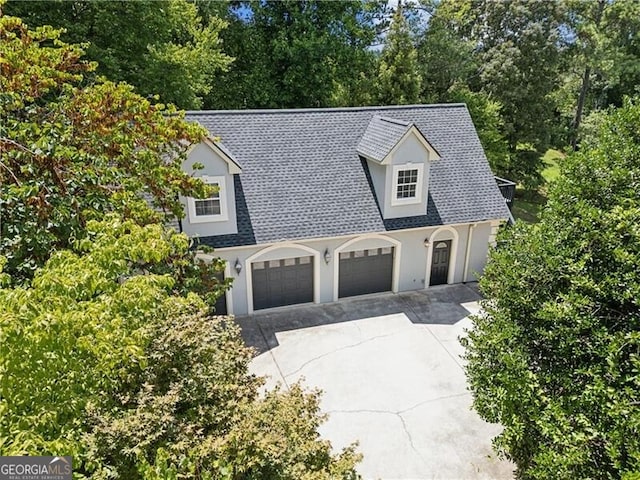 view of front facade featuring a garage, driveway, a shingled roof, and stucco siding