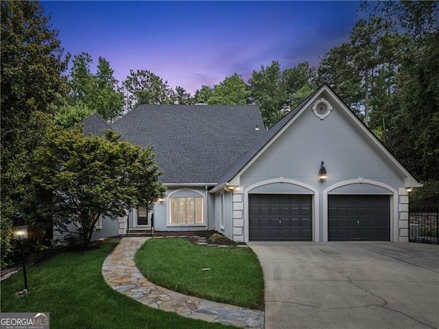 view of front of home with a lawn, concrete driveway, roof with shingles, an attached garage, and stucco siding