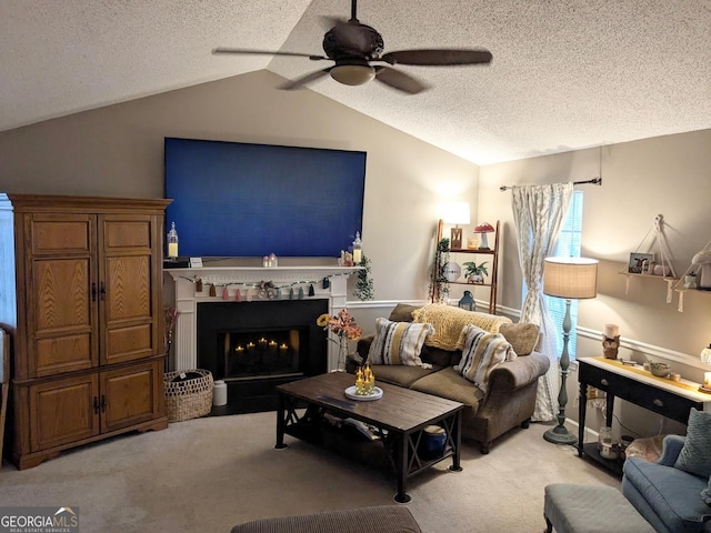 living room with carpet floors, lofted ceiling, a fireplace with flush hearth, ceiling fan, and a textured ceiling