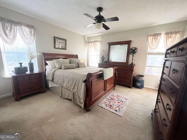 bedroom featuring light carpet, baseboards, a ceiling fan, and a textured ceiling