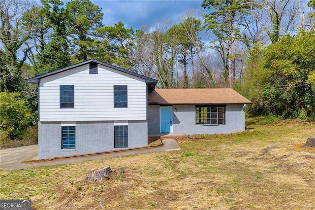 tri-level home with a front yard and brick siding