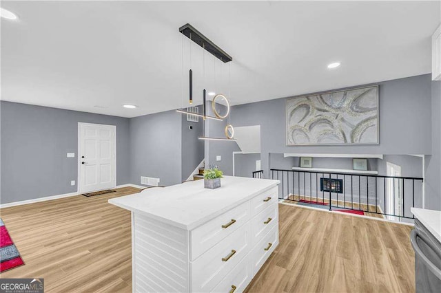 kitchen with light countertops, light wood finished floors, white cabinetry, and baseboards