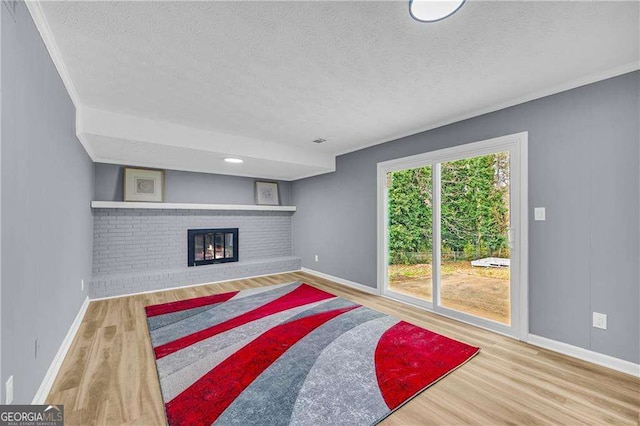 living area featuring a brick fireplace, a textured ceiling, and wood finished floors