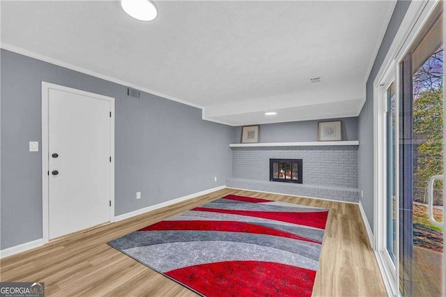 living area with ornamental molding, a brick fireplace, visible vents, and wood finished floors