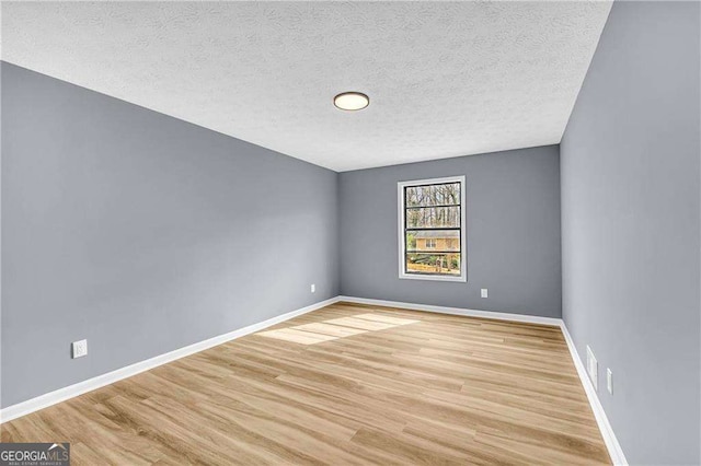 unfurnished room with baseboards, a textured ceiling, and light wood finished floors