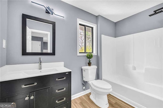 full bath featuring bathtub / shower combination, toilet, vanity, wood finished floors, and baseboards