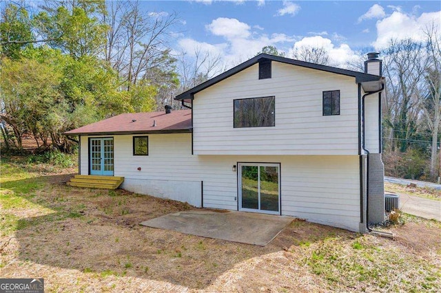 rear view of house with entry steps, a patio area, a chimney, and central AC unit