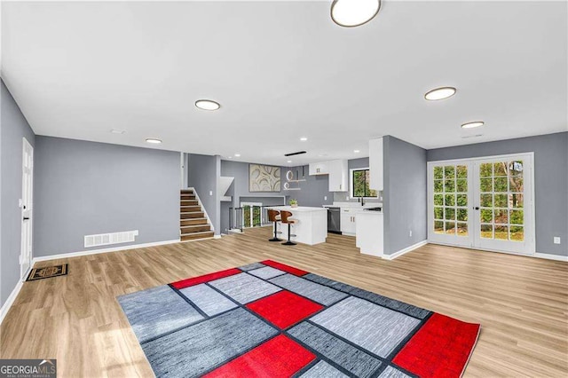 exercise room featuring visible vents, french doors, light wood-style flooring, and baseboards